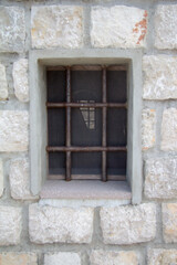 Fototapeta na wymiar Old window with grate in stone building