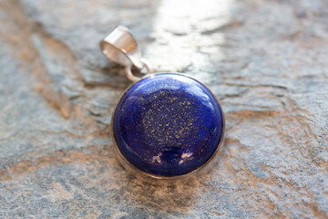 Sterling silver pendant with mineral lapis lazuli gemstone on rocky background