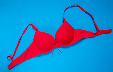 Bright red bra on a blue background. copy space. top view - obrazy, fototapety, plakaty