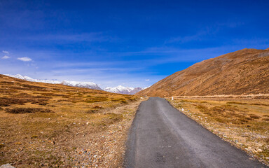 Cold desert barren landscape of Spiti mountain valley with sparse grass vegetation of bunchgrass, located high in rain shadowed region of Himalayas in Himachal Pradesh, India.