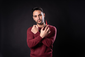 Man with scissors in hands with red sweater and black background
