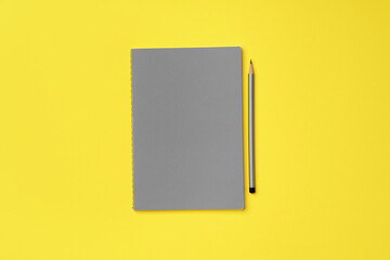 Gray notepad with pencil on yellow background
