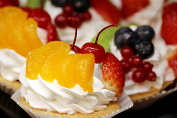 Creamy cake with fresh fruits and berries. Sweet dessert with tangerines, strawberries, cherries and blueberries