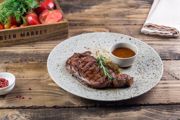 Grilled red beef pork meat barbecue steak fillet with rosemary sprig and hot sauce served on plate