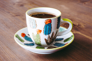 Turkish coffee on the wooden table. Turkish coffee in a cactus patterned colorful cup.