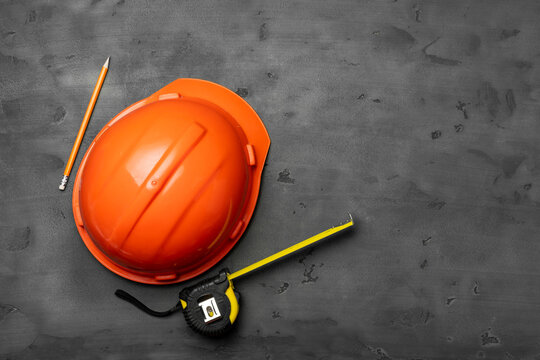 Orange hardhat, ruler and pencil on black background
