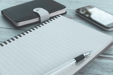 Business and finance concept. Selective focus of Pen,notebook and mobile phone on wooden table.