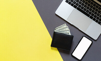 Laptop, mobile phone with empty screen and wallet with paper money on the illuminating yellow and grey background. Space for your text . Flat lay top view.