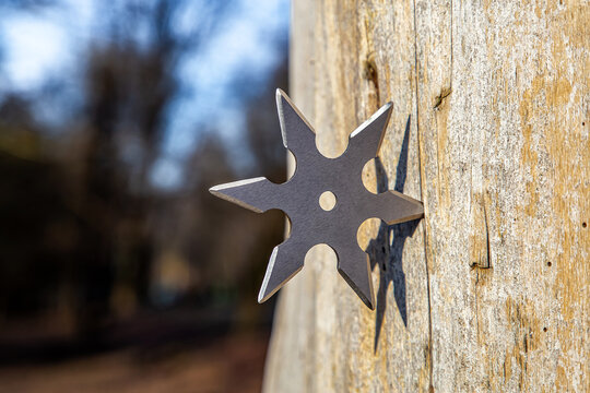 Shuriken (throwing star), traditional japanese ninja cold weapon stuck in wooden background