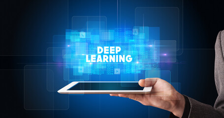 Young business person working on tablet and shows the inscription: DEEP LEARNING