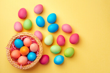 Fototapeta na wymiar Decorative nest with colorful Easter eggs on yellow background