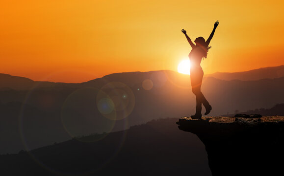 free and happy woman raises her arms at sunset. Concept of power and determination.