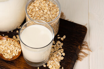 Glass of milk and oat flakes on wooden table