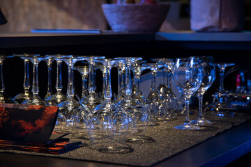 Empty wine, water, juice glasses on bar, bar interior, equipment for parties in dark light