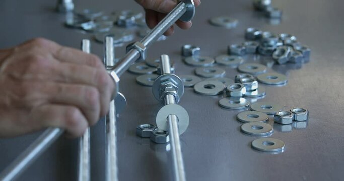 Furniture assembling worker prepares threaded rod and nuts making industrial style design shelves, close up on hand screwing nut, real people