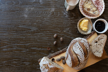 Flat Lay top down photo of Sour Dough Bread Breakfast, coffee and butter on wood cutting board with wood background © Matthew