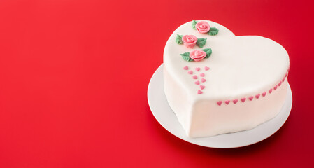 Heart cake for St. Valentine's Day, Mother's Day, or Birthday, decorated with roses and pink sugar hearts on red background	