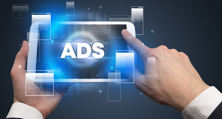Close-up of a hand holding tablet with ADS abbreviation, modern technology concept