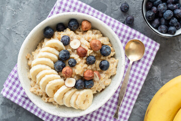 Oatmeal porridge with blueberry, banana and hazelnut. Vegan vegetarian porridge oats with fruits and nuts top view