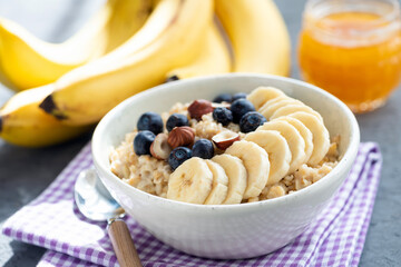 Healthy breakfast oatmeal bowl with fruits and nuts on a purple table napkin. Vegan oatmeal with...
