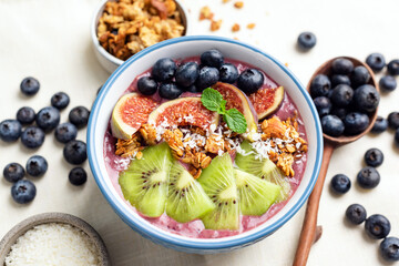 Vegan fruit smoothie bowl with blueberries, figs, kiwi and granola. Clean eating, dieting, sustainable lifestyle concept
