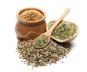 Seeds mix pile with sunflower, sesame, linseed and pumpkin seed with peeled hemp seed in wooden spoon and golden linseed, linen seeds in clay pot isolated on white background