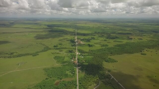 From the top view of a long straight road across a green savanna