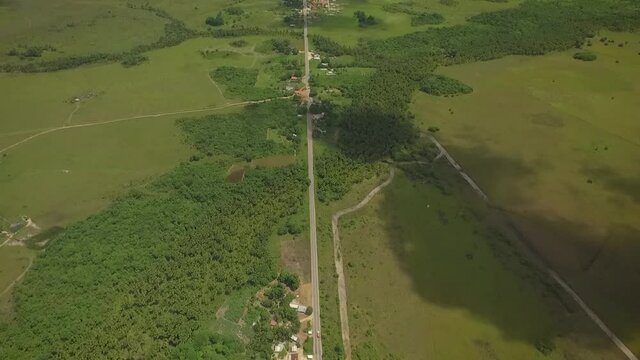 Aerial view of a long straight road across a green savanna
