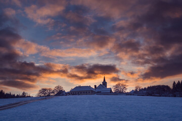 village with a church on a hill at sunset in winter, beautiful sky with illuminated clouds, Vezovata Plane, Czech republic