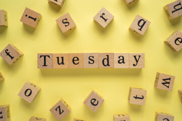 Text TUESDAY on wooden cubes with yellow background