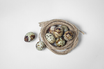 Quail eggs on a white background. Healthy eating. Quail eggs lie in a jute thread nest