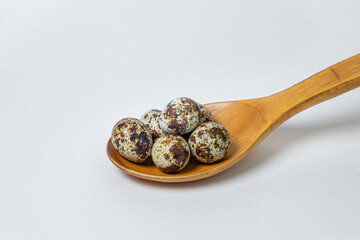 Quail eggs on a white background. Healthy eating. Quail eggs lie in a wooden spoon