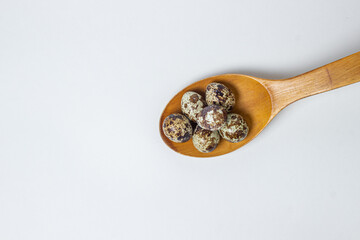 Quail eggs on a white background. Healthy eating. Quail eggs lie in a wooden spoon