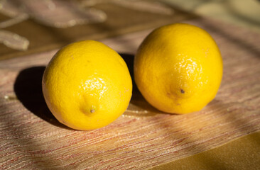 Pair of yellow lemons on a golden cream table cloth during golden hour reflecting light vitamin C source for healthy immune system
