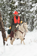 adult cowboy deer hunter riding white horse in mountain wilderness