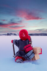 christmas elf carrying presents walking in snow into a sunset