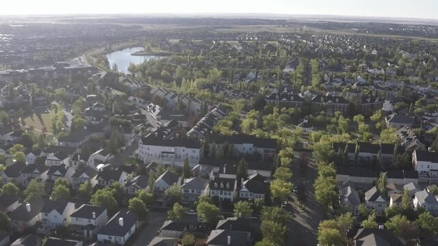 aerial fly over inverness elgin hills south east calgary alberta during sunrise on a hot summer morning in Canada where the residential community resembles brick homes of Scotland in the UK Britain.