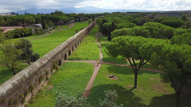 Biker And A Man Walking On The Trail In Parco degli Acquedotti (Park of the Aqueducts) In Rome, Italy On A Sunny Day - aerial drone