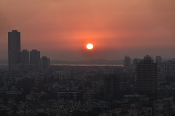 Fototapeta na wymiar sun sets into arabian sea behind the silhouette city of mumbai borivali ,India ,Maharashtra. Beautiful Sunset with orange sky color .