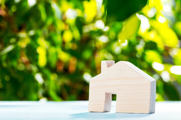 Obraz na płótnie Canvas Toy wooden house on wooden table against foliage background
