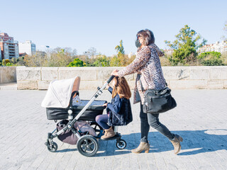 Young Girl With Her Daughter Walking The Streets With The Baby Carriage