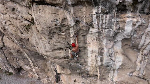 Male rock climber climbing steep rock face in Getu Valley, China, aerial view