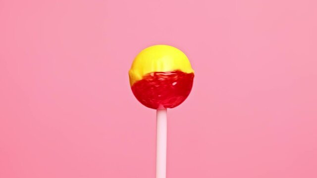 Colorful lollipop candy rotates. Strawberry banana sweetness on pink background. 