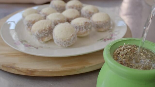 Pouring water into Argentine mate and a young man grabs a cornstarch alfajor in the morning for breakfast. Slow Motion. 120 fps.