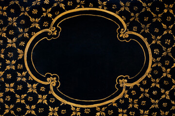 Golden frame painted on black wooden texture background with floral decoration