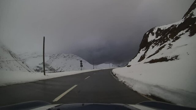une seule voiture roule avec une camera embarqu&eacute;e sur le col de la Furka il ne fait pas beau temps et il y a de la neige sur les c&ocirc;t&eacute;s de la route