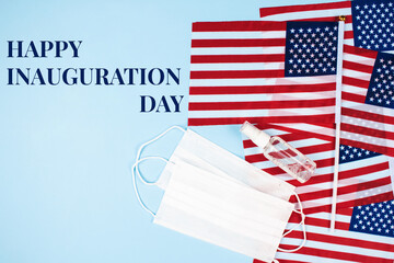 Happy Inauguration Day - creative composition with USA flags on blue background, hand sanitizer and disposable face masks, copy space for text. Inauguration Day 2021 concept, selective focus