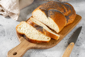 Poppy seed bun. Bread with poppy seeds on the light gray kitchen table. Homemade cakes with poppy seeds