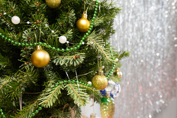 green decorated christmas tree with golden balls on gray background