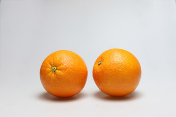 Two whole freestanding orange fruits next to each other on a white background